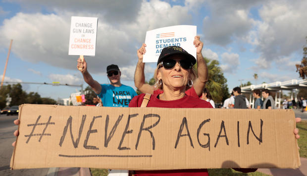 People hold signs while rallying in the street during "March for Our Lives" in Miami 