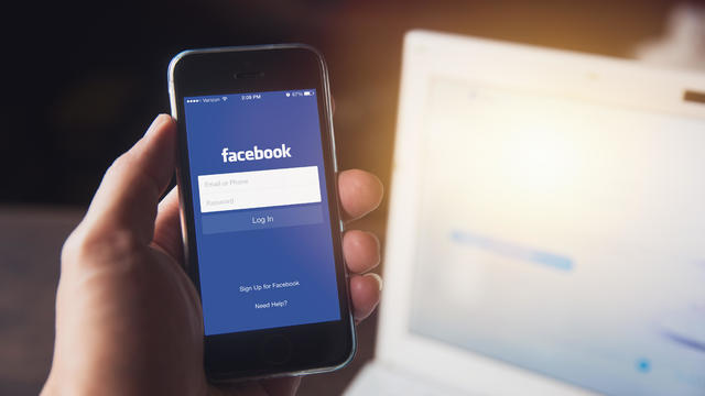 Facebook app on iPhone with computer laptop background - Facebook logo generic 