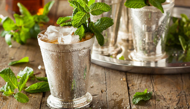 A frosty mint julep in a metal cup with a mint garnish 