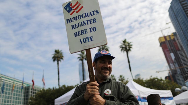 A Democratic Party worker holds up a sign encouraging immigrants who have become new U.S. citizens to sign up to vote in the upcoming midterm elections outside a naturalization ceremony in Los Angeles 