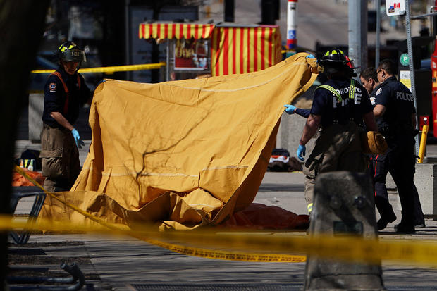 Emergency officials cover a body with a tarp at the scene of an incident where a van struck multiple people in Toronto 