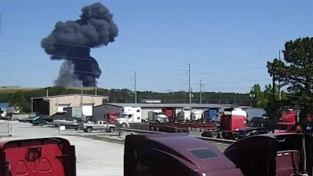 Smoke rises after a military cargo plane crashed onto a Georgia highway May 2, 2018, in this surveillance video provided by Meadowbrook Leasing LLC. 