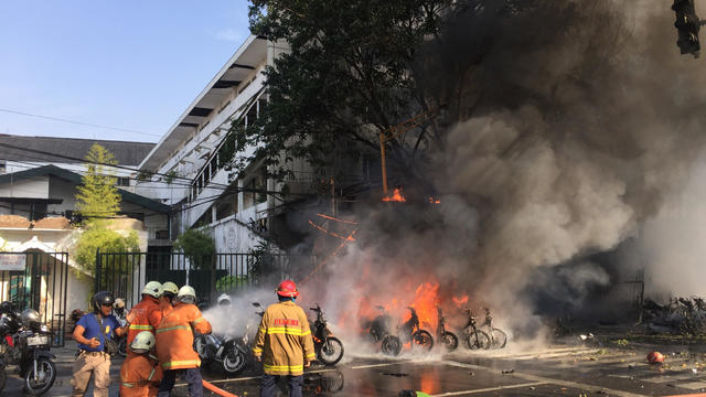 Firefighters try to extinguish a blaze following a blast at the Pentecost Church Central Surabaya (GPPS), in Surabaya, East Java 