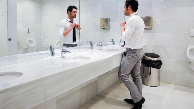 Man getting dressed in a public restroom with mirror 