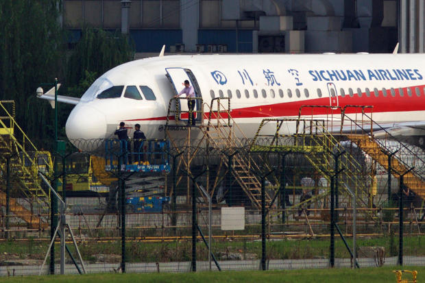 Workers inspect a Sichuan Airlines aircraft that made an emergency landing after a windshield in the cockpit broke off at an airport in Chengdu, China, May 14, 2018. 