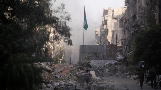 A boy stands on the rubble of damage buildings in Yarmouk Palestinian camp in Damascus 