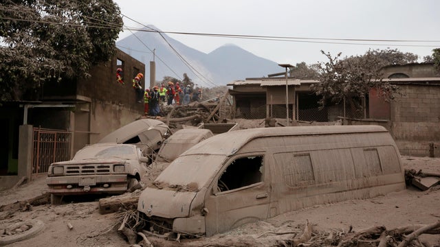 Firefighters and rescue workers look for bodies and survivors at an area affected by the eruption of the Fuego volcano in the community of San Miguel Los Lotes in Escuintla 