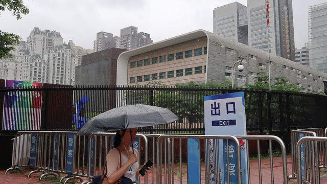 A woman shields herself from the rain as she walks past U.S. Consulate in Guangzhou 