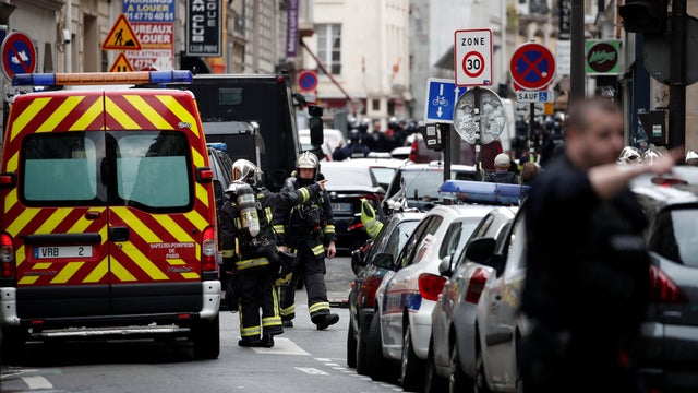 French police and firefighters secure the street as a man has taken two people hostage at a business in Paris 