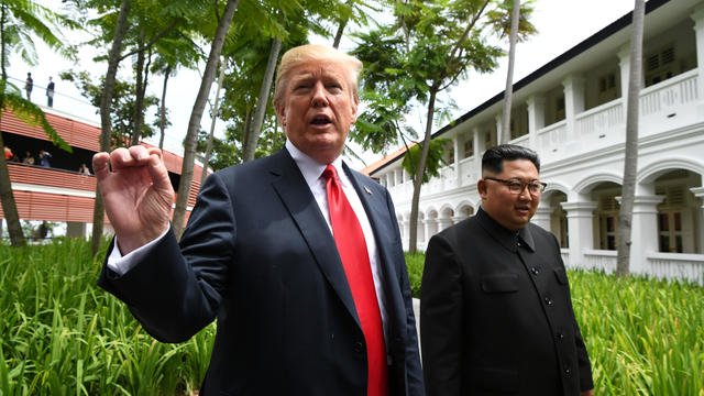 U.S. President Donald Trump gestures as he walks with North Korean leader Kim Jong Un in the Capella Hotel after their working lunch, on Sentosa island in Singapore 