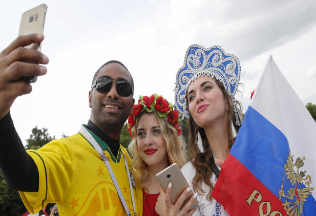 A Brazil fan takes a selfie with Russian supporters in a fan zone near the main building of the Moscow State University in Moscow on June 14, 2018. 