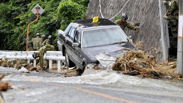Japan Ground Self-Defense Force members search around a damaged taxi on a street which was flooded by torrential rain in Hiroshima 