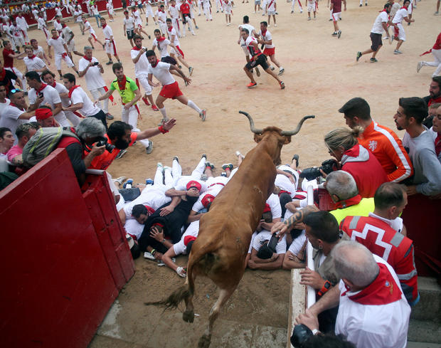 A wild cow leaps over revellers after the seventh running of the bulls of the San Fermin festival in Pamplona 