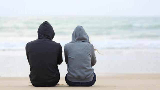 Sad couple sitting on the beach 