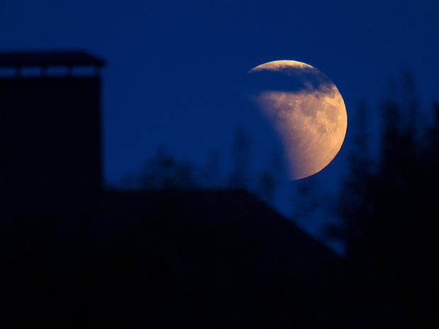 Full moon during an eclipse rises behind a house on the outskirts of Minsk 