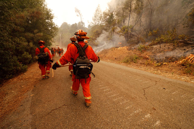 An inmate fire crew walks towards active fire while they work to stop the spread of the Carr Fire, west of Redding 
