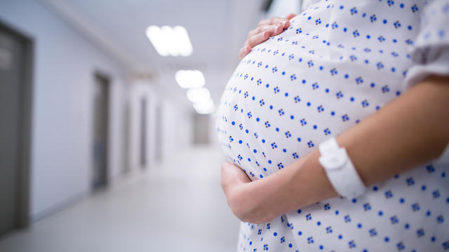 Mid section of pregnant woman standing in corridor 