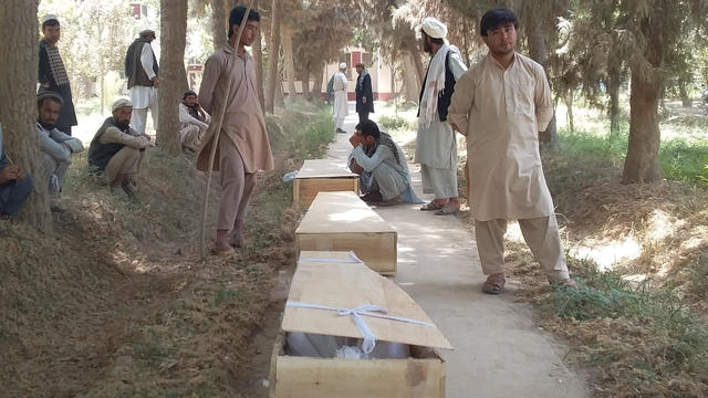 Relatives mourn next to the coffins of policemen who were killed after a Taliban attack on a military outpost in Baghlan 