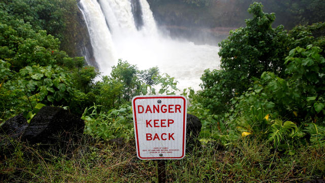 A sign warns of danger at a waterfall swollen by rain from Hurricane Lane in Hilo 