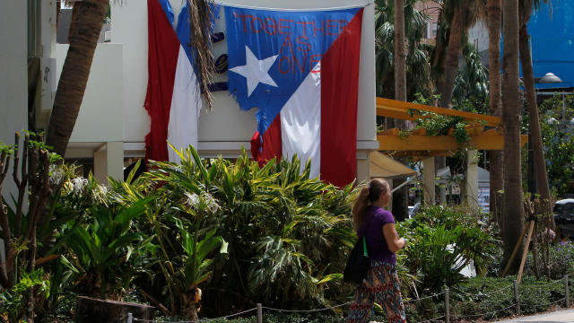 "Together as One" reads on a torn Puerto Rican flag hanging from a hotel in the tourist zone of el Condado in San Juan, Puerto Rico, on Oct. 4, 2017. 