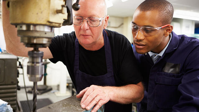 Engineer Teaching Apprentice To Use Milling Machine 