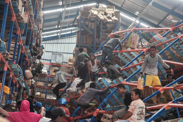 Earthquake and tsunami victims look for goods to use in a warehouse in Palu, Central Sulawesi 