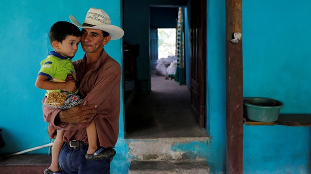 Jose Guardado, 42, a deportee from the U.S. carries his youngest son Neimar, 3, as he arrives at his home in Eden, Lepaera, Honduras 