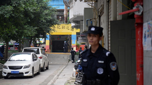 Police officers are seen outside the gate of a kindergarten where a woman armed with a kitchen knife attacked children, in Chongqing 