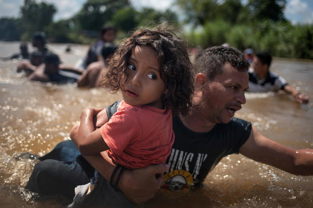 Migrant carries girl through the Suchiate River into  Mexico from Guatemala in Ciudad Hidalgo, Mexico 