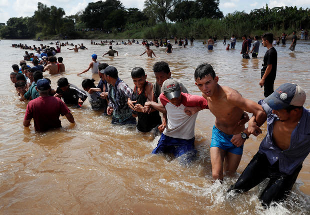 Migrants, part of a caravan travelling to the U.S., make a human chain to pull people from the river between Guatemala to Mexico in Ciudad Hidalgo and continuing to walk in Mexico 