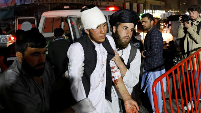 Afghan men carry an injured person to a hospital after a suicide attack in Kabul 