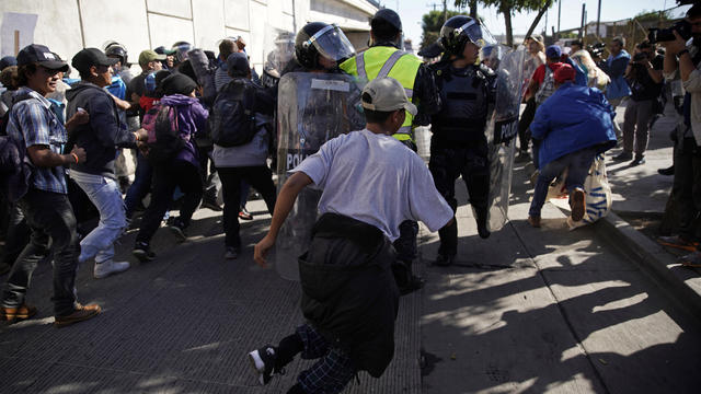 Migrants break past a line of police as they run toward the Chaparral border crossing in Tijuana, Mexico, Nov. 25, 2018, near the San Ysidro entry point into the U.S. 