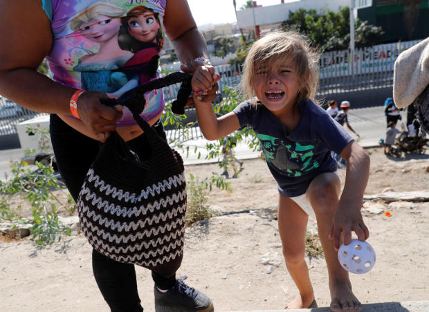 A migrant girl from Honduras, part of a caravan of thousands traveling from Central America en route to the United States, cries after running away from tear gas thrown by the U.S. border control near the border wall between the U.S. and Mexico in Tijuana 