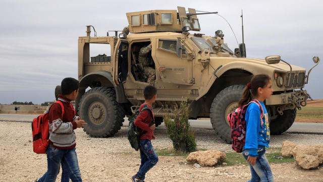 FILE PHOTO: Syrian schoolchildren walk as U.S. troops patrol near Turkish border in Hasakah 