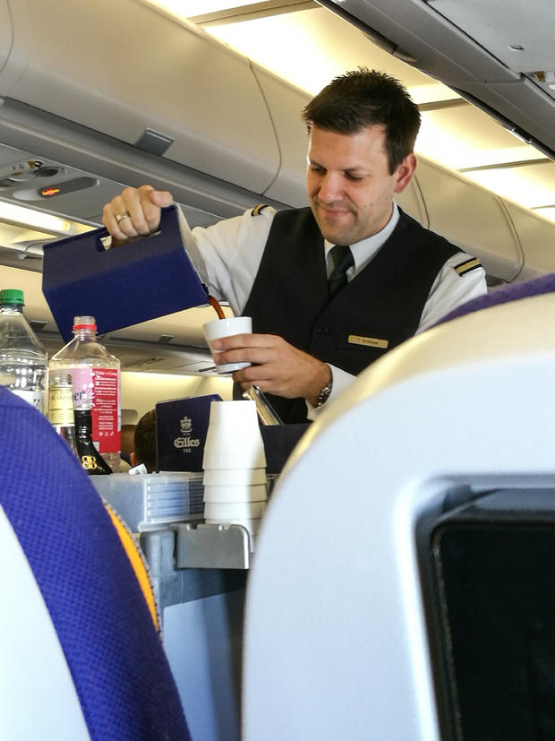 A male flight attendant serving in the economy class. 