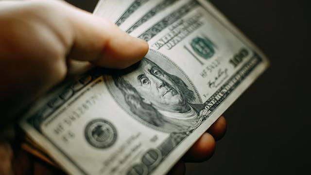 Man hand with a stack of hundred US dollars bills, close up 