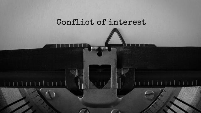 Text Conflict of interest typed on retro typewriter 