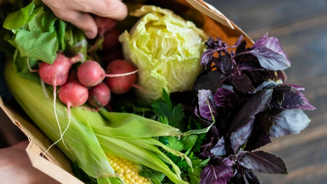 hands holding package with healthy raw fresh food on dark wooden surface 