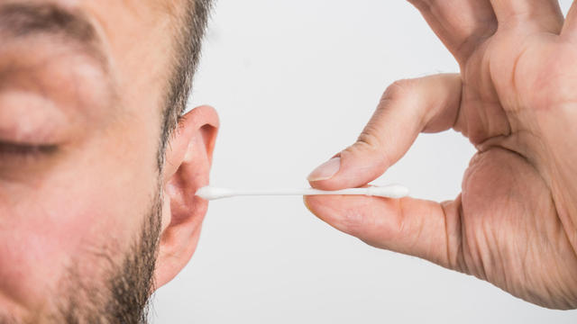 Man removing wax from ear using Q-tip 