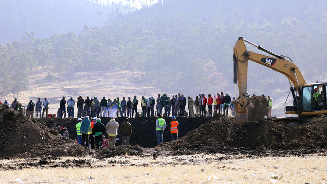 Members of the search and rescue mission look on as a digger searches for dead bodies of passengers at the scene of the Ethiopian Airlines Flight ET 302 plane crash, near the town of Bishoftu, southeast of Addis Ababa 