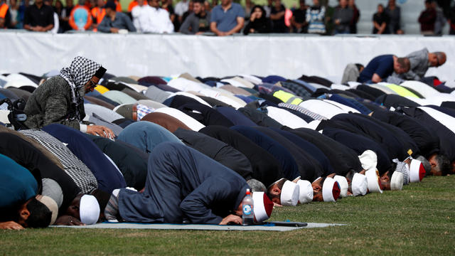 People perform the Friday prayers at Hagley Park outside Al-Noor mosque in Christchurch 