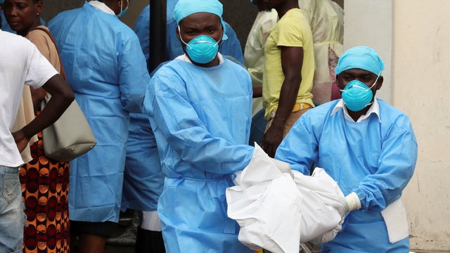 Medical staff carry the body of a one-year-old child who died at a health centre dealing with water borne diseases in Beira 
