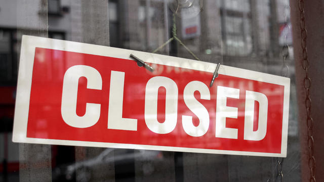 Red and white closed sign hanging in a shop window 