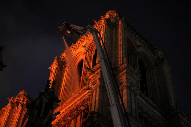 Paris Fire brigade members spray water to extinguish flames as the Notre Dame Cathedral burns in Paris 