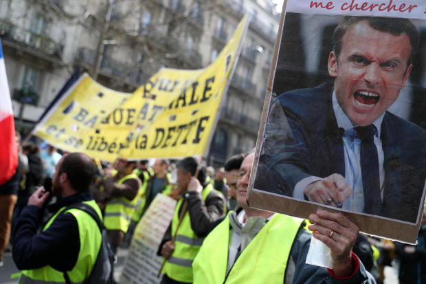 A protester holds an image of French President Emmanuel Macron shouting during an anti-government demonstration called by the so-called yellow vest (gilets jaunes) movement in Paris, on March 23, 2019. 