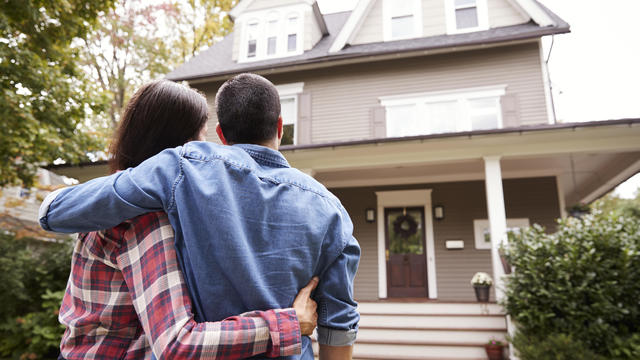 Rear View Of Loving Couple Looking At House 