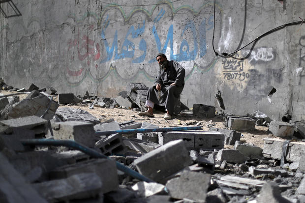 Palestinian man sits on debris near a building that was destroyed by Israeli air strikes, in Gaza City 