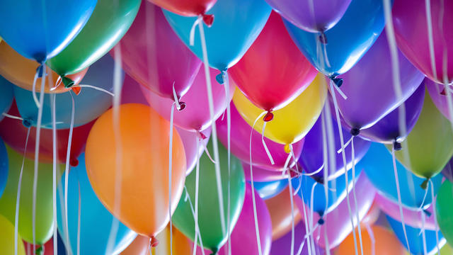 festive, colorful balloons with helium attachment to the white ribbons 