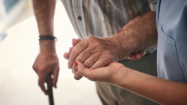 Female nurse supporting senior man to walk 