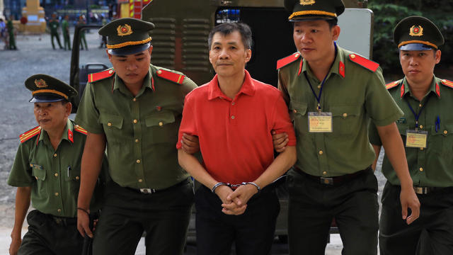 U.S. citizen Michael Nguyen is escorted by policemen before his trial at a court in Ho Chi Minh city 